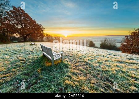 Wooden bench looking over misty High Weald landscape covered in frost at sunrise, Burwash, East Sussex, England, United Kingdom, Europe Stock Photo