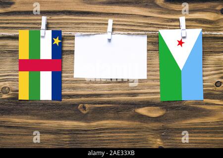 Hanging flags of Central African Republic and Djibouti attached to rope with clothes pins with copy space on white note paper on wooden background.Dip Stock Photo