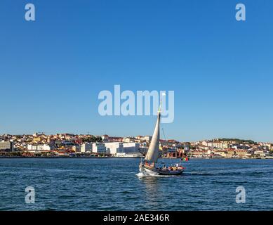 Sailboat sailing in river Tagus with cityscape on a background. Stock Photo