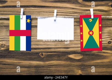 Hanging flags of Central African Republic and Grenada attached to rope with clothes pins with copy space on white note paper on wooden background.Dipl Stock Photo