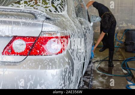 Car wash bubbles with foam in the station. Focus on the taillight Stock Photo