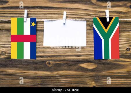 Hanging flags of Central African Republic and South Africa attached to rope with clothes pins with copy space on white note paper on wooden background Stock Photo