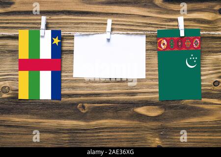 Hanging flags of Central African Republic and Turkmenistan attached to rope with clothes pins with copy space on white note paper on wooden background Stock Photo