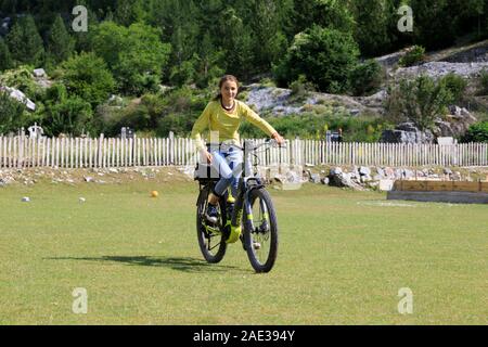 Theth, Albania, July 5 2019: An Albanian girl in Theth is riding an e-bike from a tourist Stock Photo