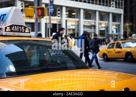 NEW YORK CITY, USA - 17 APRIL 2011:  An urban NYC view over the rear of a yellow taxi cab looking towards shoppers in midtown Manhattan. Stock Photo