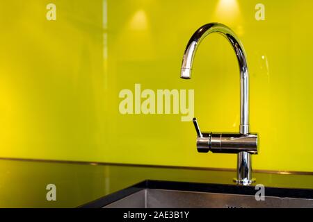 Modern stainless steel faucet and sink near poisen green wall, retro design Stock Photo
