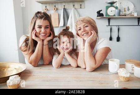 Nice portrait. Mother, grandmother and daughter having good time in the kitchen Stock Photo