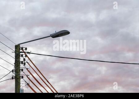 Local domestic electricity distribution pole with street light. Metaphor National Grid, power distribution, also 'high wire act', street lighting. Stock Photo