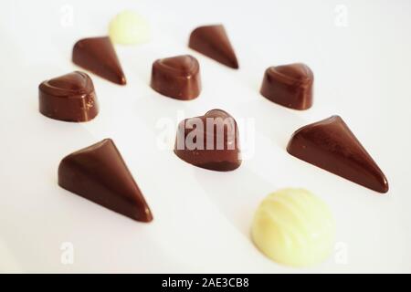 Tasty candies from dark and white chocolate isolated on white background close up. Candy from dark chocolate is heart-shaped. Stock Photo