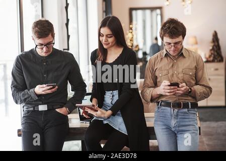 Busy people. Group of students in eyewear standing in the learning room at daytime Stock Photo
