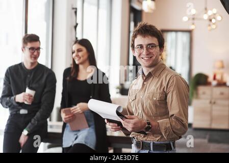 Manager is smiling. Group of students in eyewear standing in the learning room at daytime Stock Photo