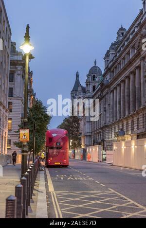 Rear view of red London bus parked in a side street, off Whitehall, in central London, UK at dusk. Stationary bus from behind in yellow BUS STAND zone. Stock Photo