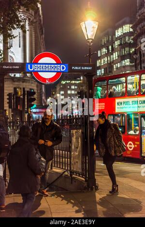 City of London lit up at night. People outside entrance to Charing Cross Underground Station, Trafalgar Square, central London UK. Double-decker bus. Stock Photo