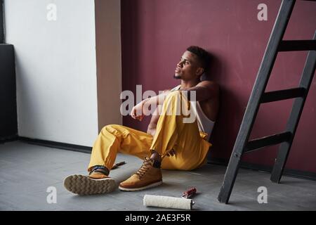 Thoughtful look. Young african american worker in the yellow uniform have some job Stock Photo