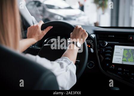 Need to test the navigation system. Close up view of woman's hands in the beautiful modern black colored car Stock Photo