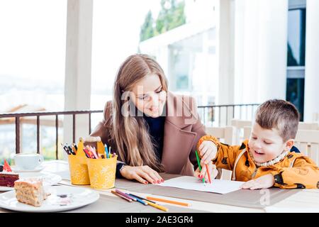 mother and son in the restaurant painted pencils before eating Stock Photo