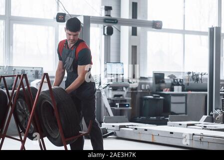 Professional equipment. Mechanic holding a tire at the repair garage. Replacement of winter and summer tires Stock Photo