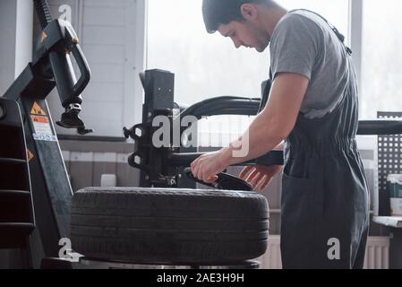 Item in hands. Young man works with wheel's disks at the workshop at daytime Stock Photo