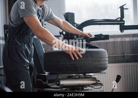 Performs an order. Young man works with wheel's disks at the workshop at daytime Stock Photo