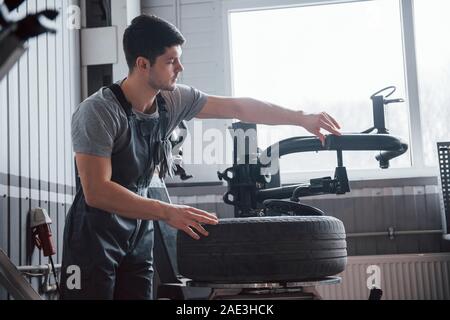 Alone in the room. Young man works with wheel's disks at the workshop at daytime Stock Photo