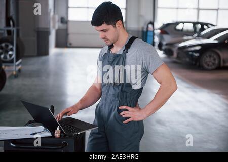 Thoughtful look. Worker stands indoors in uniform does reports, calculations and looking at the plans Stock Photo
