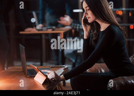 Busy woman. Attractive brunette businesswoman works in the office at nightime Stock Photo