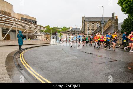 Edinburgh Marathon Festival 2019 runners run past Holyrood Palace & Scottish Parliament building on wet day, Edinburgh, Scotland, UK Stock Photo