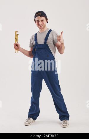 Happy worker. Man in blue uniform stands against white background in the studio Stock Photo