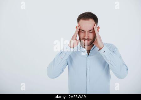 Having headache. Man in official clothes stands against white background in the studio Stock Photo