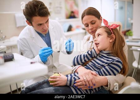 Girl at male dentist having toothache