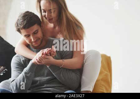 Embracing and have good time. Happy couple relaxing on the yellow sofa in the living room of their new house Stock Photo