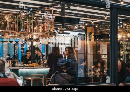 London, UK - November 24, 2019: View through the window of women talking inside Buns and Buns restaurant in Covent Garden Market, one of the most popu Stock Photo