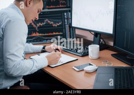 New points. Man working online in the office with multiple computer screens in index charts Stock Photo