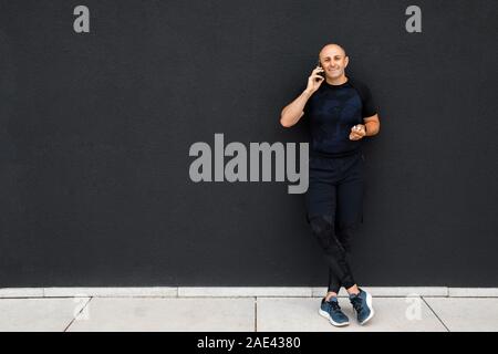 https://l450v.alamy.com/450v/2ae4380/happy-young-sporty-man-talking-on-phone-having-break-after-training-standing-at-black-wall-2ae4380.jpg