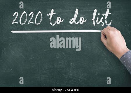 Close up of human hand writing 2020 New Year to do List on Blackboard Stock Photo