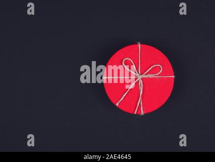 Closed red round gift box on black background. the view from the top. Gift for the holidays of New Year, Christmas, Valentine's day, March 8. Stock Photo