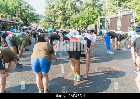 Adults are doing physical exercises in the park, Ukraine. Group sport activities outdoors in summer to maintain health. Sport for all ages concept Stock Photo