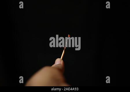 Burnt extinguished match held in hand on black rugged backgrounds Stock Photo