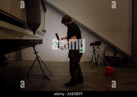 Marine engineer technician working on oiling a boat in a workshop Stock Photo