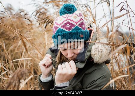 portrait of woman hiding behind her coat thinking looking sad Stock Photo