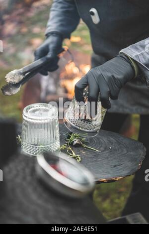 Someone smokes a glass with a lump of charcoal to make a smoky cocktai Stock Photo