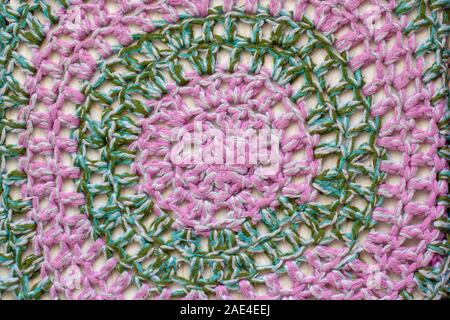 Fabric texture. Knitted circular patterns of pink and green wool. Stock Photo