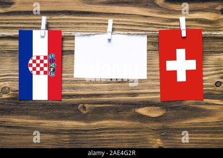 Hanging flags of Croatia and Switzerland attached to rope with clothes pins with copy space on white note paper on wooden background.Diplomatic relati Stock Photo