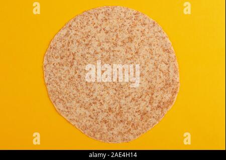 One round tortilla isolated on yellow background Stock Photo