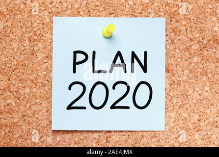 Text Plan for year 2020 handwritten on blue sticky note pinned on cork bulletin board. Stock Photo
