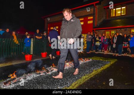 Bridport, Dorset, UK.  6th December 2019.  Members of the public walking across hot coals as they take part in a charity firewalk at Bridport Community Fire Station in Dorset in aid of the Fire Fighters Charity.  Picture Credit: Graham Hunt/Alamy Live News. Stock Photo