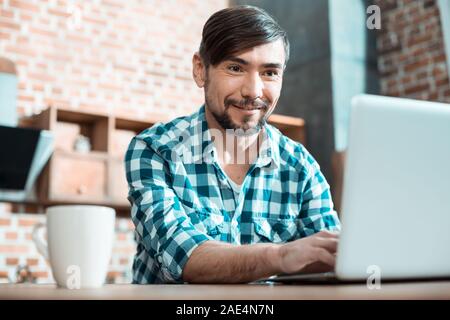 Nice positive man working on a laptop Stock Photo