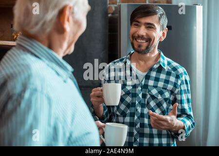 Happy delighted man smiling to his father Stock Photo