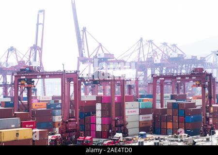 An industrial scene in the Chinese mainland of brightly coloured containers and cranes on a foggy day in an industrial estate. Stock Photo