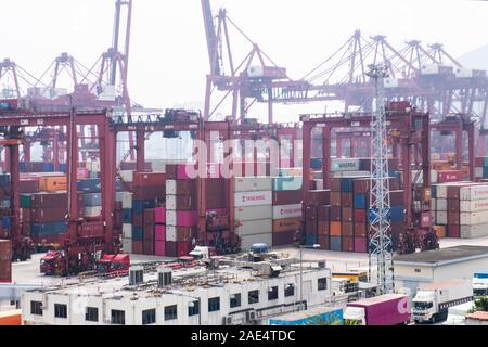 An industrial scene in the Chinese mainland of brightly coloured containers and cranes on a foggy day in an industrial estate. Stock Photo